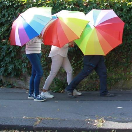 Menschen, die hinter bunten Regenschirmen laufen
